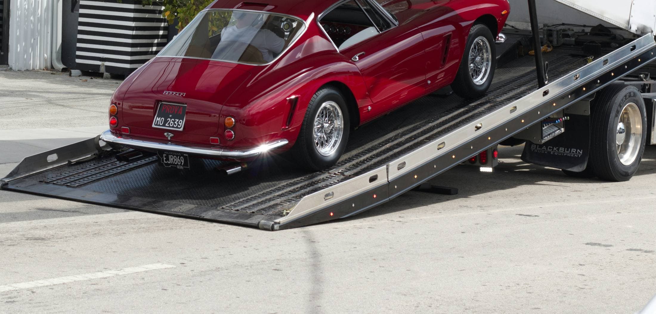 A classic red Ferrari being loaded up the ramp onto an auto-transport truck