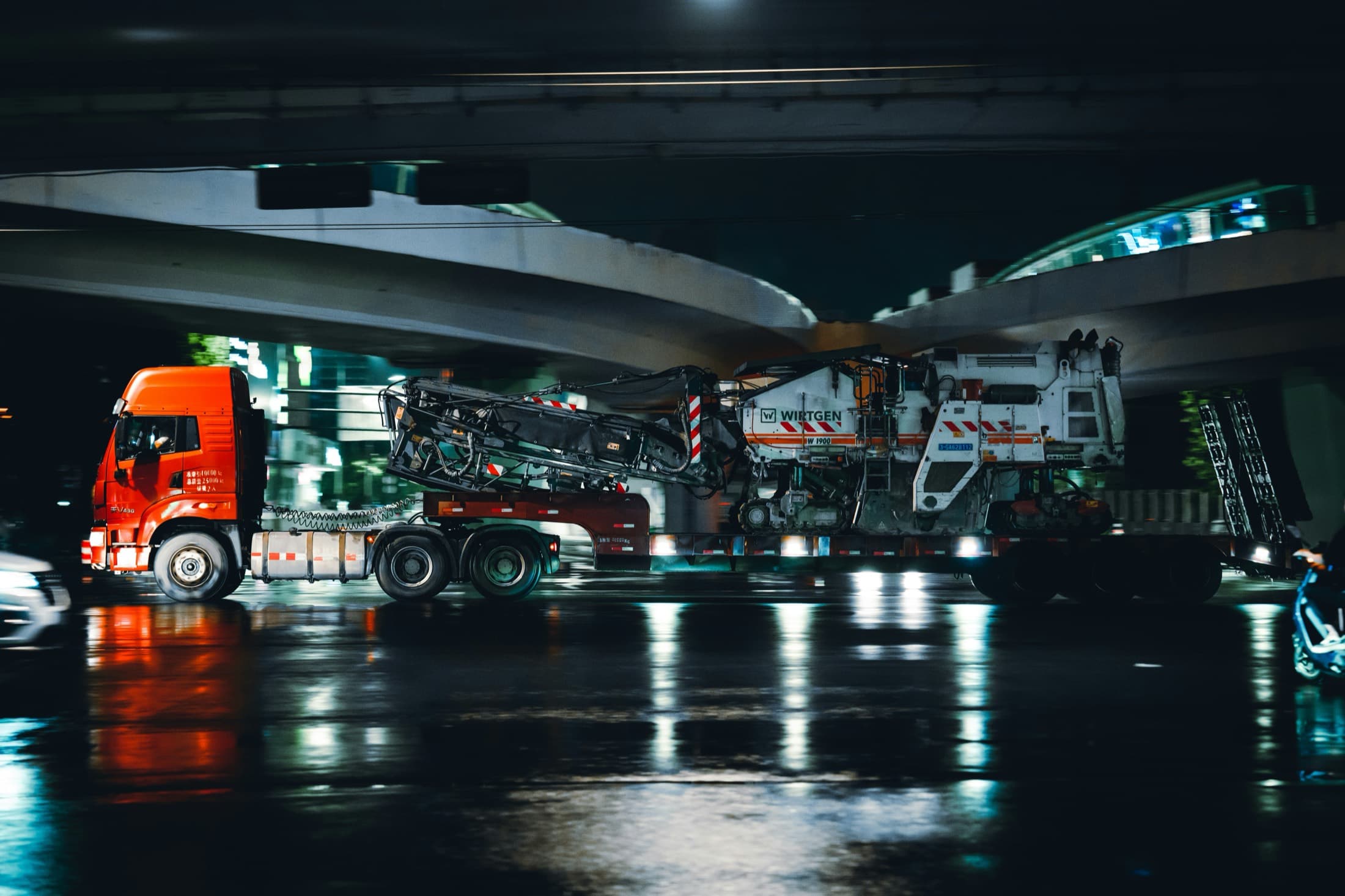 A transport truck hauling at night through the city, wet streets